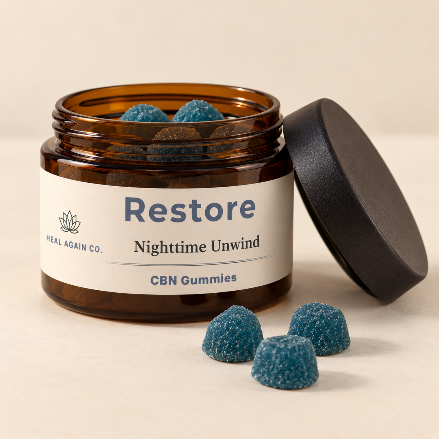Open Heal Again Co. Restore CBN Gummies jar with blue sugar-coated gummies and a black lid beside it.
