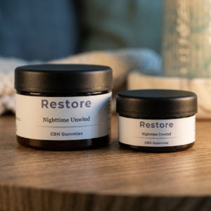 Front view of two container sizes of premium botanical Restore CBN sleep gummies by Heal Again Co., crafted to support deep evening stillness and natural overnight recovery.